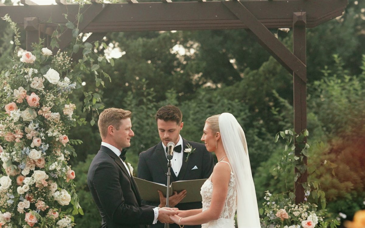 Mike and Sam exchanging vows beneath a floral arch at their Crystal Springs Resort ceremony